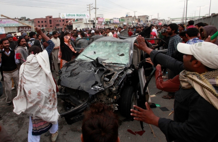 Protesters from the Christian community attack a car during clashes with riot police, a day after suicide attacks on two churches in Lahore, March 16, 2015. Pakistani police broke up Christian protesters in the eastern city of Lahore with tear gas and baton charges on Monday, a day after suicide bombers killed at least 16 people outside two churches, police said. The protesters, angry at the lack of security for Christians in the majority-Muslim country, blocked a major highway in the city.