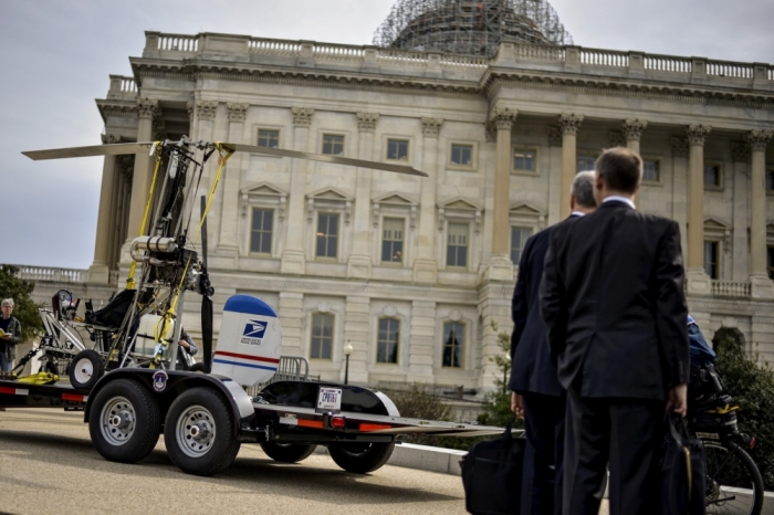 People watch as a gyro copter that was flown onto the grounds of the U.S. Capitol is towed from the west front lawn in Washington, April 15, 2015. A bomb squad has determined there was nothing hazardous on the small, open-air helicopter that landed on the grounds of the U.S. Capitol on Wednesday, the U.S. Capitol Police said in a statement, adding that the 'gyro copter' will be moved to a secure location.