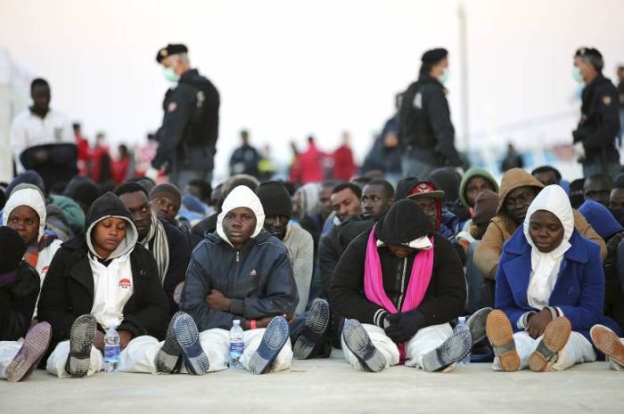 Migrants rest after they disembarked in the Sicilian harbour of Augusta, April 16, 2015. Italian police arrested 15 African men suspected of throwing about a dozen Christians from a migrant boat in the Mediterranean on Thursday, as the crisis off southern Italy intensified.