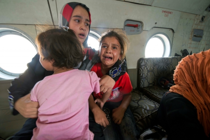 A woman and children react in a military helicopter after being evacuated by Iraqi forces from Amerli, north of Baghdad August 29, 2014. A home to around 180,000 people, mostly Turkmen Shiites, the small town of Amerli, north of Baghdad, is still holding out against repeated attacks by Islamic State fighters despite the fall of all the 34 villages surrounding it.
