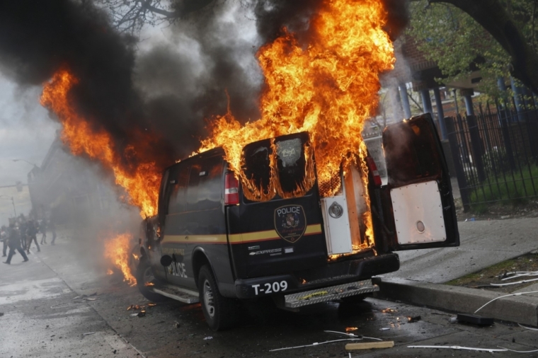 A Baltimore Metropolitan Police transport vehicle burns during clashes in Baltimore, Maryland, April 27, 2015. Maryland Governor Larry Hogan declared a state of emergency and activated the National Guard to address the violence in Baltimore, his office said on Monday. Several Baltimore police officers were injured on Monday in violent clashes with young people after the funeral of a black man, Freddie Gray, who died in police custody, and local law enforcement warned of a threat by gangs.