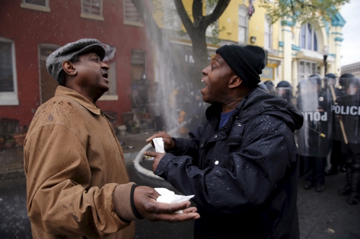 A Baltimore resident (R) trying to restore order in his neighborhood speaks to a protester during clashes in Baltimore, Maryland, April 27, 2015. Maryland Governor Larry Hogan declared a state of emergency and activated the National Guard to address the violence in Baltimore, his office said on Monday. Several Baltimore police officers were injured on Monday in violent clashes with young people after the funeral of a black man, Freddie Gray, who died in police custody, and local law enforcement warned of a threat by gangs.