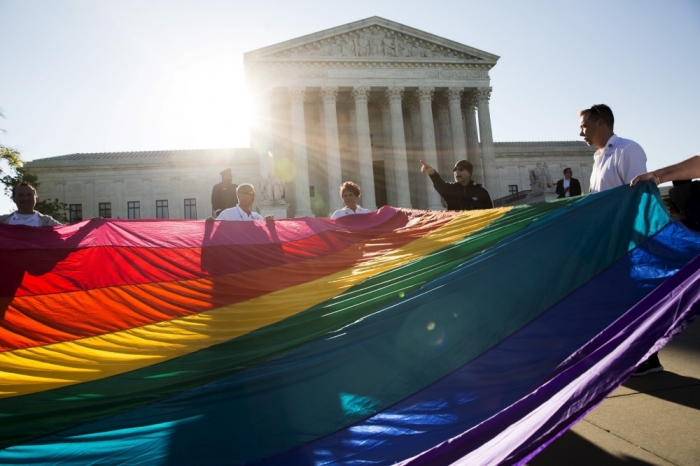 Gay marriage supporters hold a gay rights flag in front of the Supreme Court before a hearing about gay marriage in Washington, April 28, 2015. The nine justices will be hearing arguments concerning gay marriage restrictions imposed in Kentucky, Michigan, Ohio and Tennessee, four of the 13 states that still outlaw such marriages.