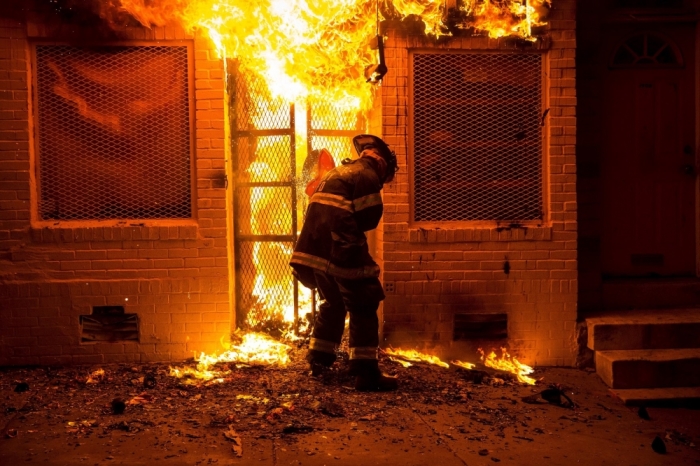 A firefighter uses a saw to open a metal gate while fighting a fire in a convenience store and residence during clashes after the funeral of Freddie Gray in Baltimore, Maryland, in the early morning hours of April 28, 2015. Baltimore erupted in violence as hundreds of rioters looted stores, burned buildings and injured at least 15 police officers following the funeral of Gray, a 25-year-old black man who died after he was injured in police custody.