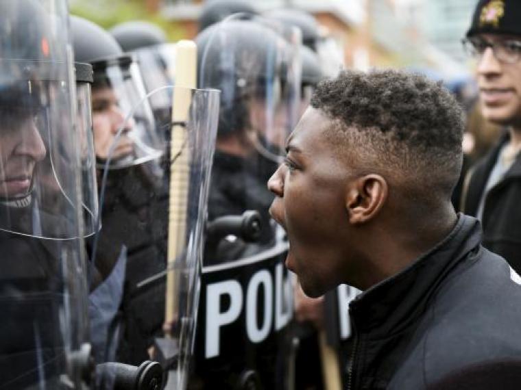 A demonstrator confronts police near Camden Yards during a protest against the death in police custody of Freddie Gray in Baltimore, Maryland, April 25, 2015. At least 2,000 people protesting the unexplained death of Gray, 25, while in police custody marched through downtown Baltimore on Saturday, pausing at one point to confront officers in front of Camden Yards, home of the Orioles baseball team.