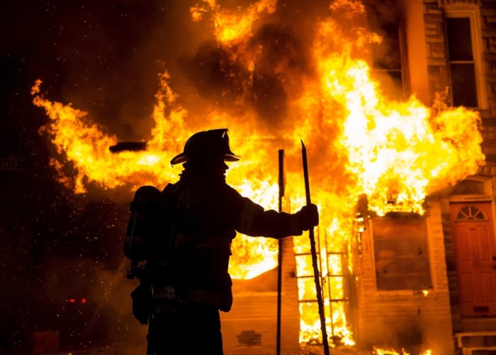 A Baltimore firefighter attacks a fire at a convenience store and residence during clashes after the funeral of Freddie Gray in Baltimore, Maryland, in the early morning hours of April 28, 2015. Baltimore erupted in violence as hundreds of rioters looted stores, burned buildings and injured at least 15 police officers following the funeral of Gray, a 25-year-old black man who died after he was injured in police custody.