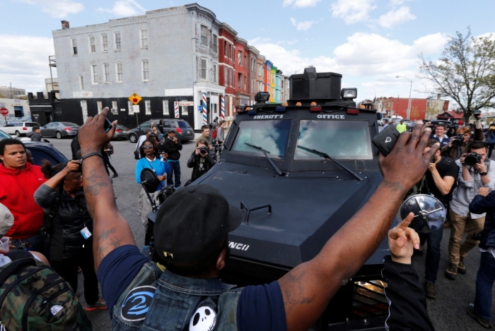 Members of the community try to force a police armored vehicle to reverse back down the street, near the site of a burned and looted CVS pharmacy, in Baltimore, Maryland, April 28, 2015. Baltimore's mayor came under criticism on Tuesday for a slow police response to some of the worst urban violence in the United States in years in which shops were looted, buildings burned to the ground and 20 officers were injured.