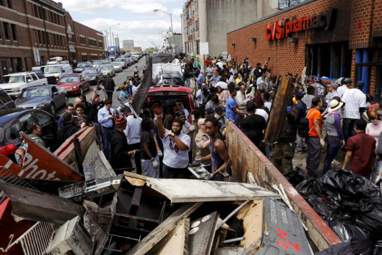 Members of the community work to clean up a recently looted and burned CVS store in Baltimore, Md.,on April 28, 2015, after looters targeted the store and rioters set fire to it.