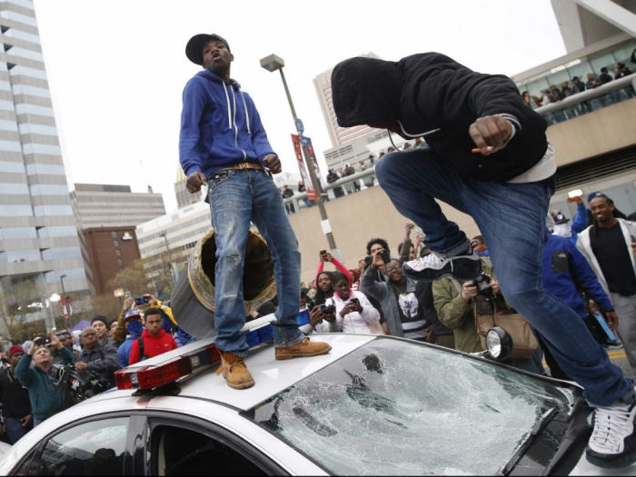 Young men damage a police car during a period of rioting after the funeral of Freddie Gray on April 27, 2015, in Baltimore, Md.