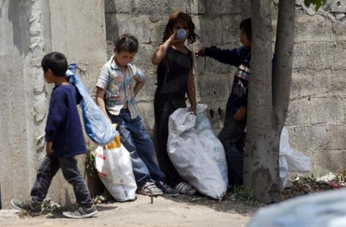 Syrian refugee children collect plastics as they stand along a street in south of Sidon, southern Lebanon June 10, 2014.
