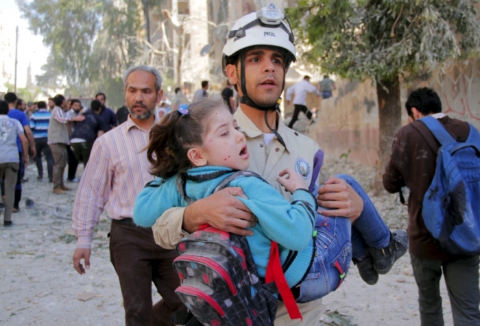 A civil defence member holds a rescued schoolgirl after what activists said was a barrel bomb dropped by forces loyal to Syria's President Bashar al-Assad and hit a school and a residential building in Seif al-Dawla neighborhood of Aleppo, Syria, May 3, 2015.