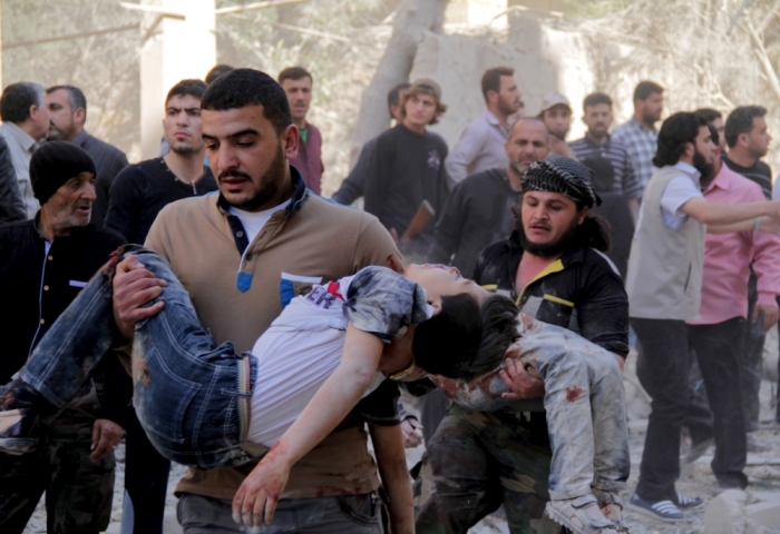 Men carry injured schoolchildren after what activists said was a barrel bomb dropped by forces loyal to Syria's President Bashar al-Assad and hit a school and a residential building in Seif al-Dawla neighborhood of Aleppo, May 3, 2015.