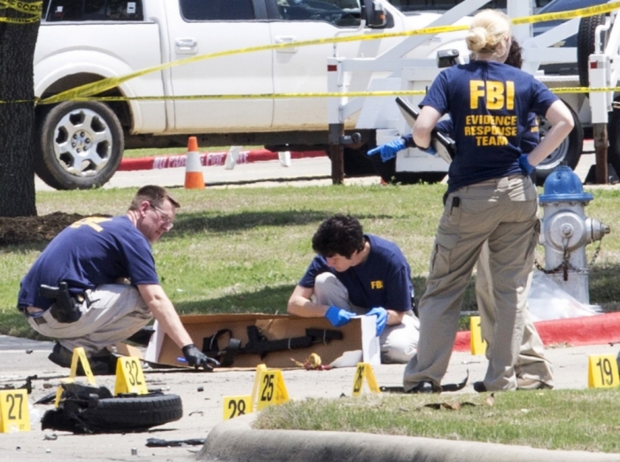 FBI investigators collect evidence, including a rifle, where two gunmen were shot dead after their bodies were removed in Garland, Texas, May 4, 2015. Texas police shot dead two gunmen who opened fire on Sunday outside an exhibit of caricatures of Muhammad that was organized by a group described as anti-Islamic and billed as a free-speech event.