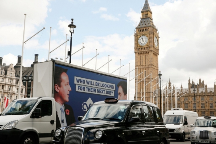 An advertising van with images of Britain's Prime Minister David Cameron and leader of the opposition Labour Party Ed Miliband drives around Parlaiment Square, central London, Britain, May 7, 2015.