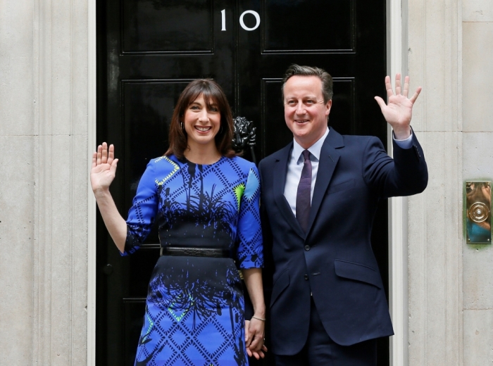 Britain's Prime Minister David Cameron and his wife Samantha wave as they return to Number 10 Downing Street after meeting with Queen Elizabeth at Buckingham Palace in London, Britain, May 8, 2015. Prime Minister David Cameron won a stunning election victory in Britain, overturning poll predictions that the vote would be the closest in decades to sweep easily into office for another five years, with his Labour opponents in tatters.