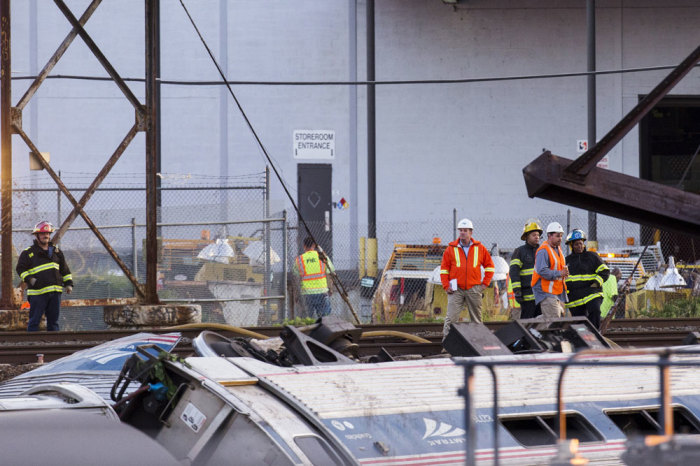 Emergency workers survey the remains of a derailed Amtrak train in Philadelphia, Pennsylvania May 13, 2015. An Amtrak passenger train with more than 200 passengers on board derailed in north Philadelphia on Tuesday night, killing at least five people and injuring more than 50 others, several of them critically, authorities said. Authorities said they had no idea what caused the train wreck, which left some demolished rail cars strewn upside down and on their sides in the city's Port Richmond neighborhood along the Delaware River.