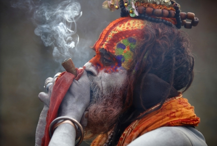 A Hindu holy man, or sadhu, smokes marijuana in a chillum on the premises of Pashupatinath Temple in Kathmandu February 17, 2015. Hindu holy men from Nepal and India come to this temple to take part in the Maha Shivaratri festival annually for holiday when it is legal to smoke the otherwise illegal drug. Celebrated by Hindu devotees all over the world, Shivaratri is dedicated to Lord Shiva, and holy men mark the occasion by praying, smoking marijuana or smearing their bodies with ashes.