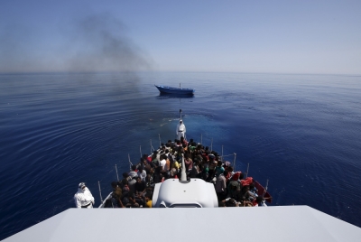 A group of 300 sub-Saharan Africans (bottom) sit on board the Italian Finance Police vessel Di Bartolo as their boat (Top) is left to adrift off the coast of Sicily, May 14, 2015. Around 1100 migrants were rescued off the coast of Sicily, about 130 miles from Lampedusa, according to the police.