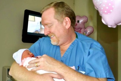 Dr. Brent Boles with a child at delivery.