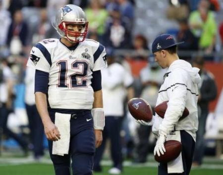 A ball boy holds footballs as New England Patriots quarterback Tom Brady (12) warms-up ahead of the start of the NFL Super Bowl XLIX... May 11, 2015 05:57pm EDT