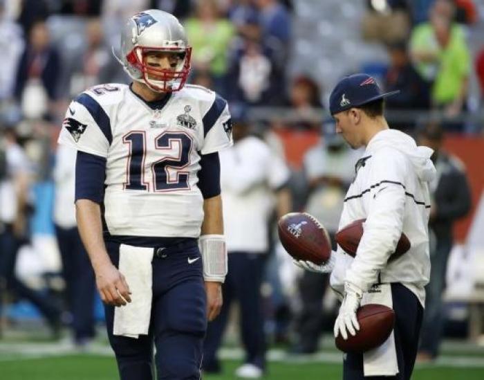 A ball boy holds footballs as New England Patriots quarterback Tom Brady (12) warms-up ahead of the start of the NFL Super Bowl XLIX... May 11, 2015 05:57pm EDT