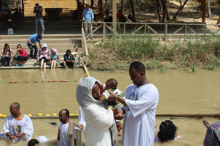 Eritrean Christians celebrate at the Jordan River in Israel while tourists look on from the nation of Jordan on the other side on Saturday May 23, 2015.