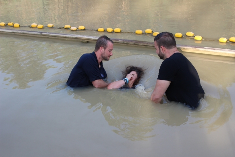 An Oral Roberts University Student hits the water during a baptism in the Jordan River that runs along the border of Israel and Jordan on Saturday May 23, 2015.