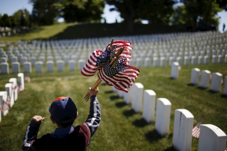 A member of the Boy Scouts of America holds flags to be placed at graves at Cypress Hills National Cemetery in Brooklyn, New York, May 23, 2015. The annual