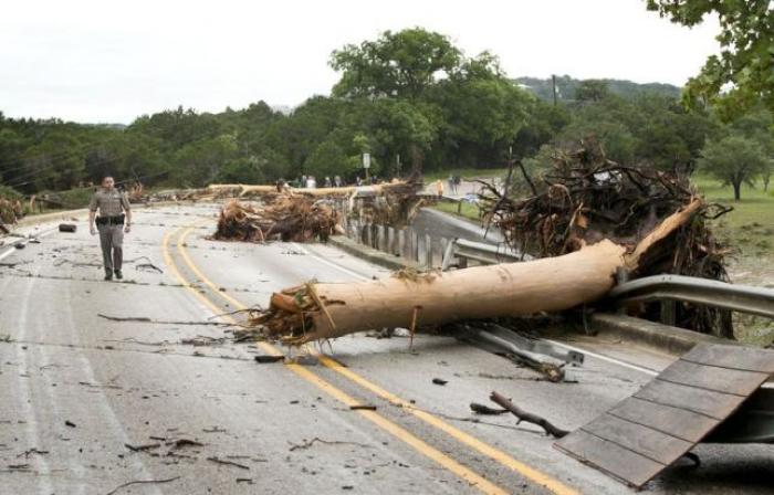 Department of Public Safety Trooper Marcus Gonzales walks on the Highway 12 bridge over the Blanco River which was blocked by large trees after flooding in Wimberly, Texas, United States May 24, 2015.