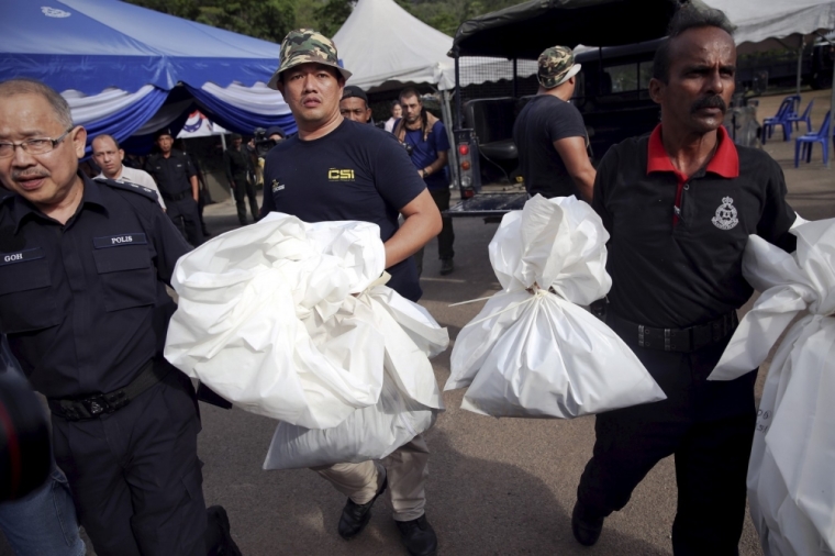 Forensic policemen carry body bags with human remains found at the site of human trafficking camps in the jungle close the Thailand border after they brought them to a police camp near Wang Kelian in northern Malaysia, May 25, 2015. Malaysian authorities have found 139 graves, and signs of torture, in more than two dozen squalid human trafficking camps suspected to have been used by gangs smuggling migrants across the border with Thailand, the country's police chief said on Monday.