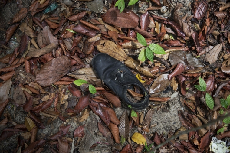 Clothes are photographed near abandoned human trafficking camp in the jungle close the Thailand border at Bukit Wang Burma in northern Malaysia, May 26, 2015. Malaysian police forensic teams, digging with hoes and shovels, began the grim task on Tuesday of exhuming the bodies of dozens of suspected victims of human traffickers found buried around jungle camps near the Thai border.
