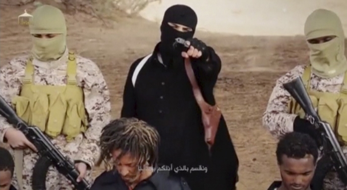An Islamic State militant holds a gun while standing behind Ethiopian Christians in Wilayat Fazzan, in this still image from an undated video made available on a social media website on April 19, 2015.