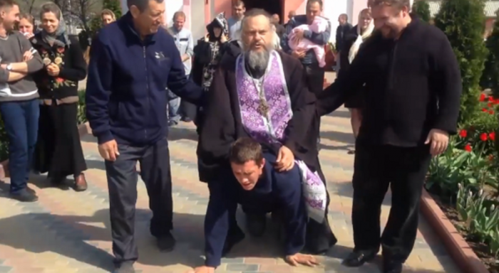 A Moldovan priest rides a man like a donkey to exorcise a demon from him.