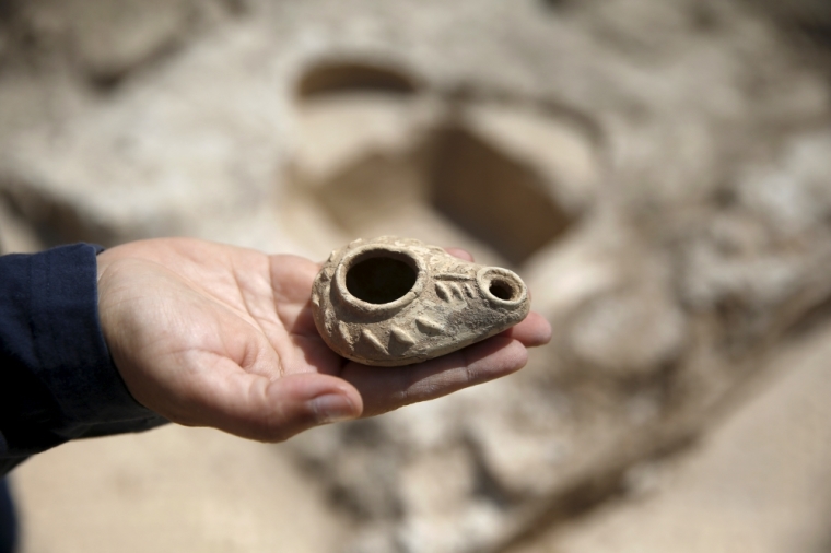 Annette Nagar, director of the excavation for the Israel Antiquities Authority, shows an ancient oil lamp unearthed at a site where a road station, dating back 1,500 years and frequented by travelers between Jerusalem and the coastal plain, was exposed, near Beit Nekofa, west of Jerusalem, Israel, June 10, 2015. A statement from the IAA said the Byzantine-period road station that included a church was discovered during a salvage dig conducted while upgrading the highway between Jerusalem and Tel Aviv.