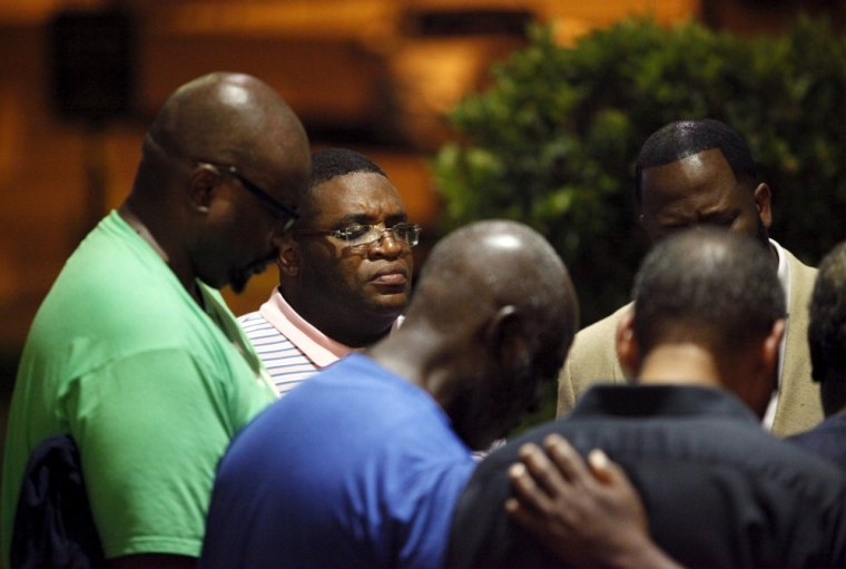 A small prayer circle forms nearby where police are responding to a shooting at the Emanuel AME Church in Charleston, South Carolina, June 17, 2015. A gunman opened fire on Wednesday evening at the historic African-American church in downtown Charleston and was still at large, a U.S. police official said, but there were no immediate confirmed reports of casualties.