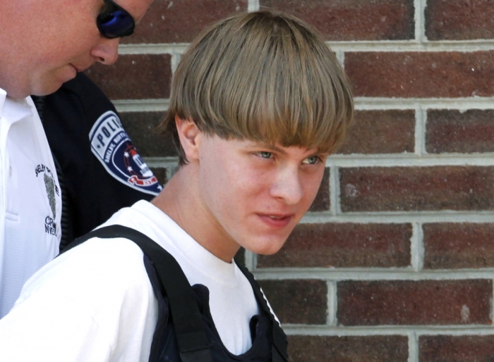 Police lead suspected shooter Dylann Roof into the courthouse in Shelby, North Carolina, June 18, 2015. Roof, a 21-year-old with a criminal record, is accused of killing nine people at a Bible-study meeting in a historic African-American church in Charleston, South Carolina, in an attack U.S. officials are investigating as a hate crime.