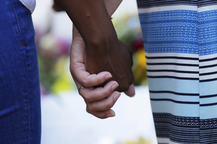 Mourners hold hands outside the Emanuel African Methodist Episcopal Church in Charleston, South Carolina, June 18, 2015, a day after a mass shooting left nine dead during a Bible study at the church. Dylann Roof, a 21-year-old white man, was arrested on Thursday on suspicion of having fatally shot nine people at the historic African-American church in South Carolina. The U.S. Department of Justice is investigating Wednesday's attack as a hate crime, motivated by racism or other prejudice.