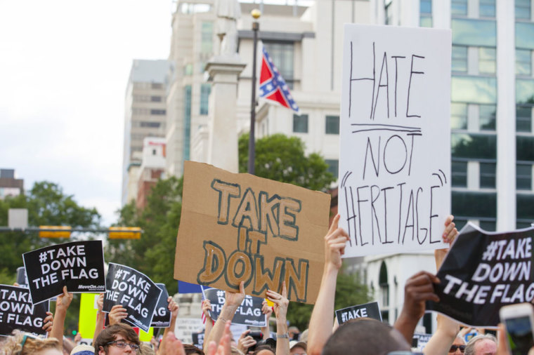 People hold signs during a protest asking for the removal of the confederate battle flag that flies at the South Carolina State House in Columbia, SC June 20, 2015.