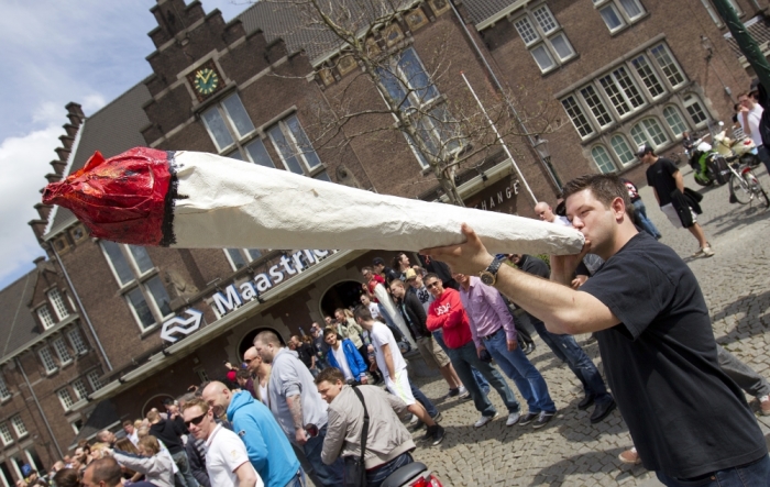 A man protesting against a ban on selling cannabis to foreigners pretends to smoke a mock joint in front of the central train station in Maastricht, Netherlands, May 1, 2012.