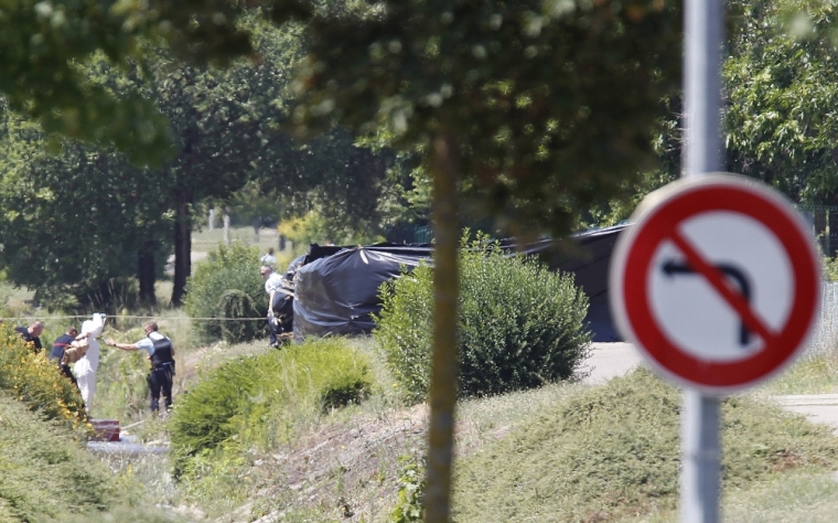 French crime scene investigators, Gendarmes and rescue forces are seen at work next to a black plastic sheet outside a gas company site at the industrial area of Saint-Quentin-Fallavier, near Lyon, France, June 26, 2015. A decapitated head covered in Arabic writing was found at a a site belonged to Air Products, a U.S.-based industrial gases technology company, in southeast France on Friday, police sources and French media said, after two assailants rammed a car into the premises, exploding gas containers.