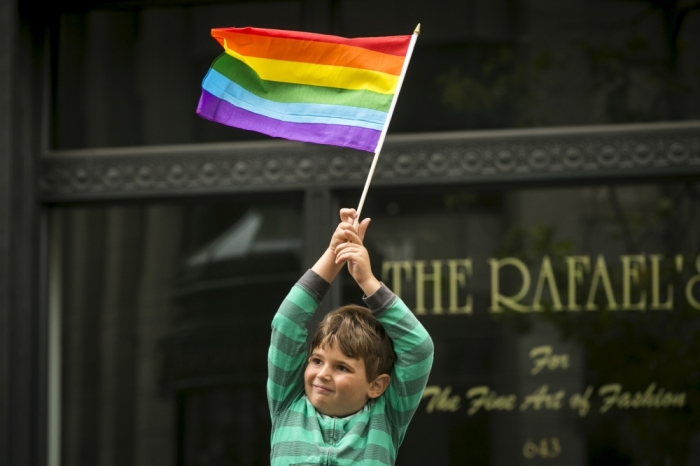 A young boy waves a rainbow flag while watching the San Francisco gay pride parade two days after the U.S. Supreme Court's landmark decision that legalized same-sex marriage throughout the country in San Francisco, California, June 28, 2015.