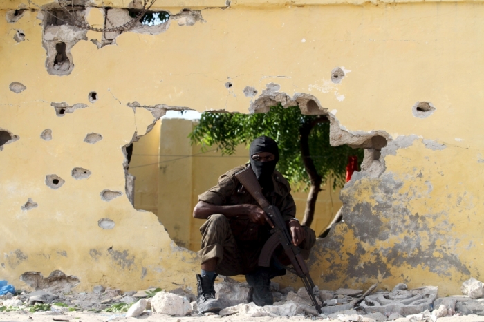 A Somali soldier takes position at the scene of a suicide attack by al Shabaab militants in capital Mogadishu, June 21, 2015. Four Islamist gunmen were killed after detonating a car bomb and shooting their way into a national intelligence agency training site, the internal security ministry said, adding that the government did not suffer any casualties during the attack.