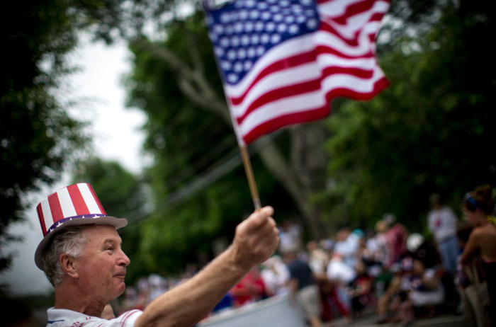 A man waves an American flag as he watches a July Fourth parade in the village of Barnstable, Massachusetts July 4, 2014. Barnstable, which is located on Cape Cod in Massachusetts and was first settled in 1639, is celebrating its 375th anniversary in 2014.