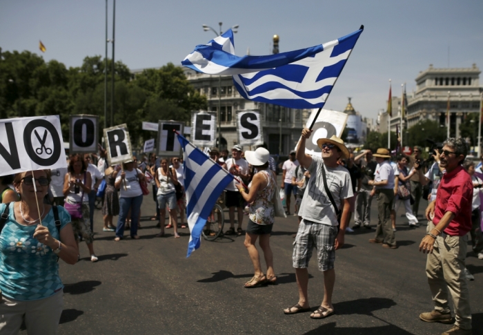 A man waves a Greek national flag during a rally in support of Greece, in Madrid July 5, 2015. Greeks voted on Sunday whether to accept or reject the tough terms of an aid offer to stave off financial collapse, in a referendum that may determine their future in Europe's common currency.