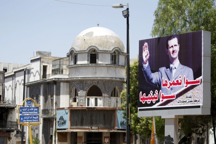 A billboard depicting Syria's President Bashar al-Assad is seen in the old city of Homs, Syria, June 3, 2015. Steady advances by insurgents on key fronts in Syria mean President Bashar al-Assad is under more military pressure than at any point in the four-year-old war. After his loss of Palmyra, a symbolic and militarily strategic city, and nearly all of Idlib province, he appears to be circling his wagons more closely to a western region that includes Damascus, Homs, Hama and the coast. The arabic on the billboard reads 'Together, we will build it.'