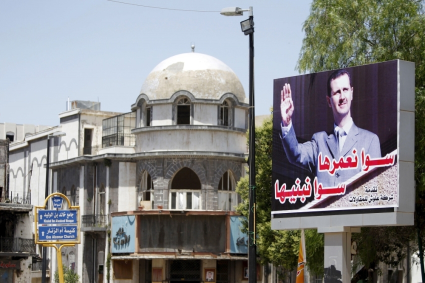 A billboard depicting Syria's President Bashar al-Assad is seen in the old city of Homs, Syria, June 3, 2015. Steady advances by insurgents on key fronts in Syria mean President Bashar al-Assad is under more military pressure than at any point in the four-year-old war. After his loss of Palmyra, a symbolic and militarily strategic city, and nearly all of Idlib province, he appears to be circling his wagons more closely to a western region that includes Damascus, Homs, Hama and the coast. The arabic on the billboard reads