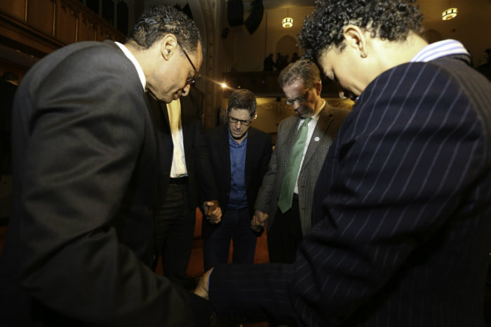 A.R. Bernard (left) of Christian Cultural Center and Mac Pier (green tie) pray with a group of supporters during the September 2014 launch of New York City-Serve.