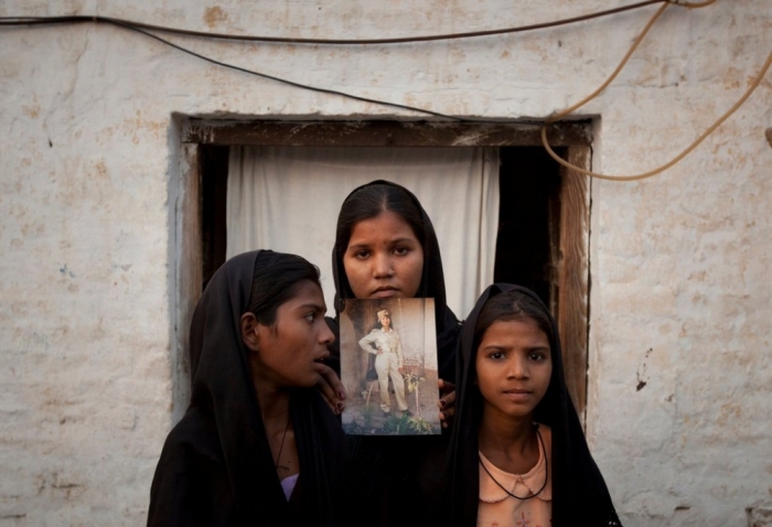 The daughters of Asia Bibi posed with an image of their mother outside their residence in Sheikhupura, located in Pakistan's Punjab Province.