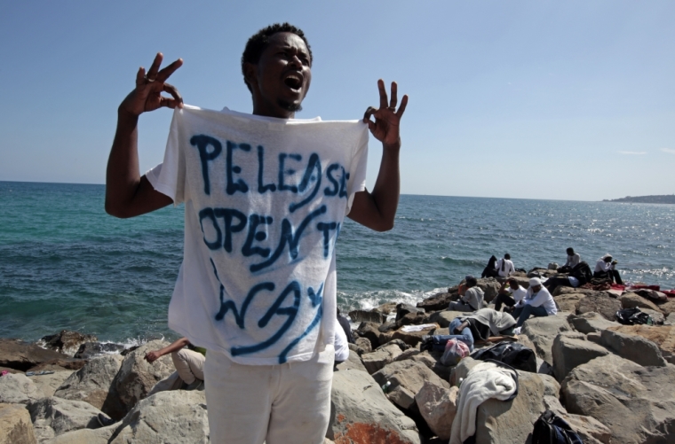 A migrant shouts a slogan as he wears a Tee Shirt with the message, 'Open The Way' as he stands on the seawall at the Saint Ludovic border crossing on the Mediterranean Sea between Vintimille, Italy and Menton, France, June 14, 2015. On Saturday, some 200 migrants, principally from Eritrea and Sudan who attempted to cross the border, were blocked by Italian police and French gendarmes.