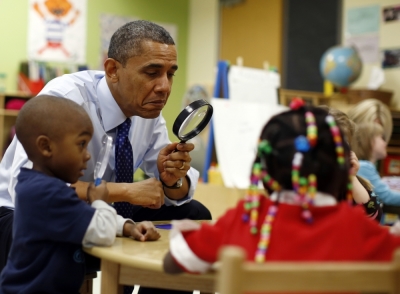 U.S. President Barack Obama uses a magnifying glass to play a game with children in a pre-kindergarten classroom at College Heights early childhood learning center in Decatur February 14, 2013.